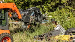 A skid steer grabs garbage with an Ignite grapple bucket.