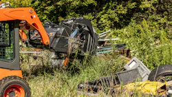 A skid steer grabs garbage with an Ignite grapple bucket.
