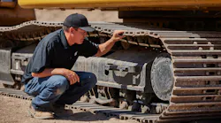 An operator inspects a Caterpillar 320 HEX undercarriage.