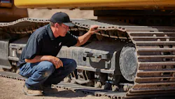 An operator inspects a Caterpillar 320 HEX undercarriage.