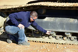 A mechanic inspecting the rollers on a Develon excavator.