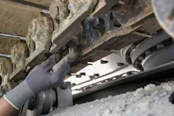 A mechanic inspects an undercarriage on a Volvo Construction Equipment excavator.