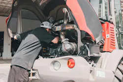 A mechanic checks the engine on a Takeuchi compact wheel loader.